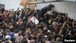 فلسطینی 18 مارچ 2024 کو فاقہ کشی کے بحران کے شکار غزہ سٹی میں UNRWA کے گودام کے باہر امداد حاصل کرنے کے لیے جمع ہیں۔
