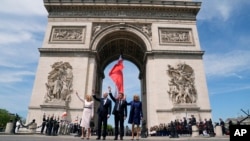 Từ trái qua, Đệ nhất phu nhân Hoa Kỳ Jill Biden, Tổng thống Hoa Kỳ Joe Biden, Tổng thống Pháp Emmanuel Macron và phu nhân Brigitte Macron vẫy chào trong buổi lễ tại Khải Hoàn Môn, ngày 8 tháng 6 năm 2024 ở Paris.