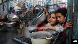 غزہ کی پٹی میں کھانا تقسیم کرنے کی ایک تنظیم کے باہر بچے اپنی باری کا انتظار کر رہے ہیں۔ 18 مارچ 2024