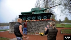 Người dân đặt hoa dưới chân tượng đài một chiếc xe tăng để kỷ niệm Ngày Chiến thắng, ngày kỷ niệm kết thúc Thế chiến thứ hai, vào ngày 9 tháng 5 năm 2009 tại thành phố Narva của Estonia. 