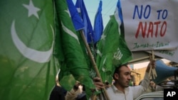A supporter of Jamaat-e-Islami (JI), a religious and political party, holds collected party flags and placards after an anti-American demonstration in Peshawar December 2, 2011. Pakistan's commanders in the wild Afghan border region can return fire if att