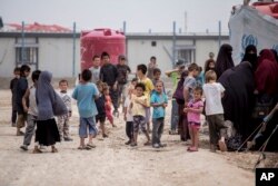 شام کےالہول کیمپ کے سامنے عورتیں اور بچےجمع ہیں جہاں 2021 کے اعداد و شمار کے مطابق اس وقت ساٹھ ہزار پناہ گزیں تھے۔ فوٹو اے پی یکم مئی 2021