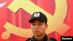 Một cảnh sát đứng canh ở phía trước tấm áp phích biểu tượng cộng sản bên ngoài Trung tâm Hội nghị Quốc gia.