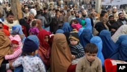 پاکستان میں مقیم افغان خاندان کوائف کے اندراج کے لیے ایک سرکاری مرکز کے باہر اپنی باری کا انتظار کر رہے ہیں۔ (فائل فوٹو)