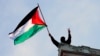 کولمبیا یونیورسٹی کا ایک احتجاجی طالب علم کیمپس کی عمارت کی چھت پر وکٹری کا نشان بناتے ہوئے فلسطین کا جھنڈا لہرا رہا ہے۔ 30 اپریل 2024
