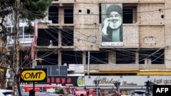 منگل کے حملے میں بیروت میں تباہ ہونے والی عمارت کے نزدیک حزب اللہ کے رہنما حسن نصر اللہ کی ایک تصویر۔ فوٹو اے ایف پی