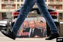 ایک گاڑی پر لٹکے پلے کارڈ پر پوٹن کی تصویر کے ساتھ یہ عبارت لکھی ہوئی نظر آ رہی ہے کہ اور روس کی سالمیت اور تحفظ کے لیے اس کے ساتھ ہیں اور آپ؟؟؟
