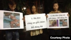 Mẹ và anh chị của nạn nhân Đỗ Đăng Dư cầm biểu ngữ phản đối. (Facebook: Dung Truong)