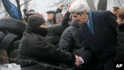 Ngoại trưởng Mỹ John Kerry bắt tay với một người biểu tình bên cạnh những chướng ngại vật tại thủ đô Kyiv của Ukraina, ngày 4/3/2014. 