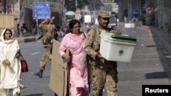 ایک فوجی اہلکار انتخابی عملے کے ساتھ سامان پولنگ اسٹیشن کی جانب لے جارہا ہے (فائل فوٹو)